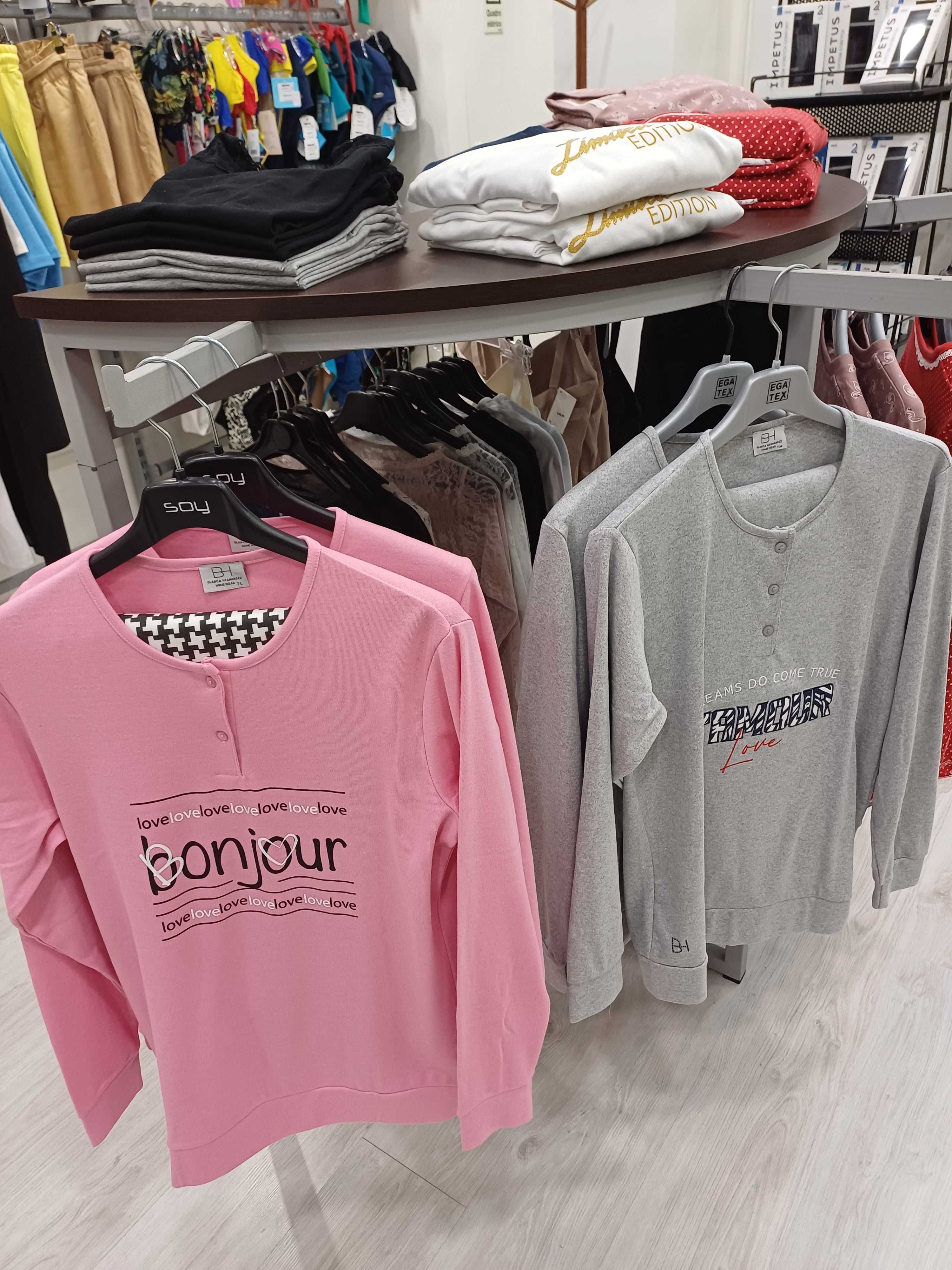 Expositor de roupa cinza com tampo em wengue, em formato de meia lua.