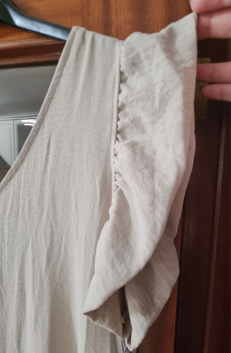 Macacão bege comprido, com folhos nos ombros. TU