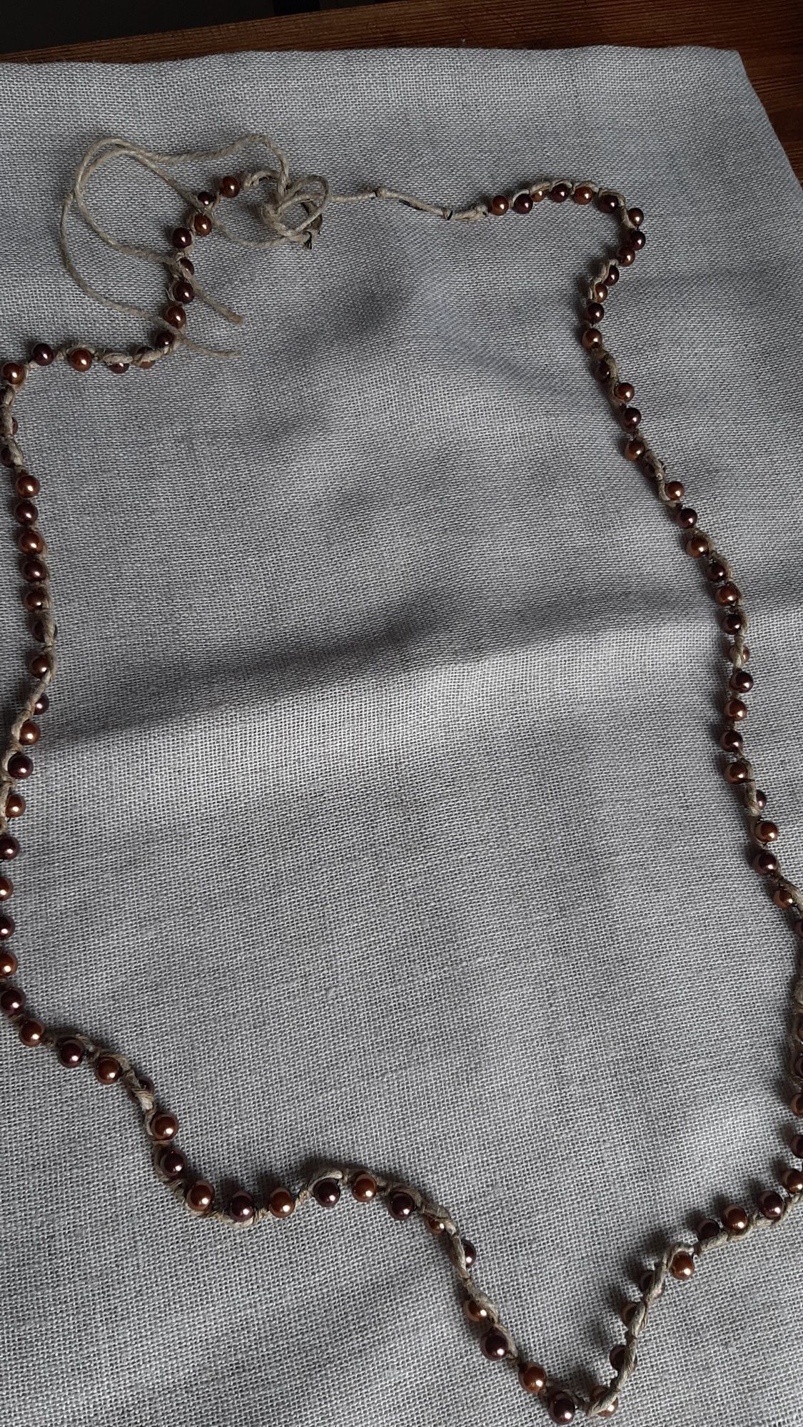 Długi sznur brązowych  pereł połączony ze sznurkiem
