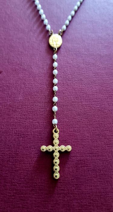 Colar dourado, em aço, em forma de terço com pequenas pérolas.