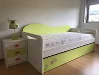 Cama individual unissexo e mesa de cabeceira.