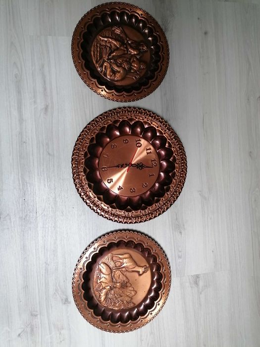 Pratos decorativos em cobre, sendo que um é relógio de parede.