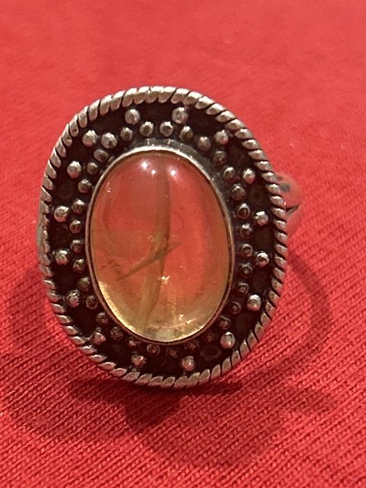 Srebrny pierścionek z żółtym oczkiem.