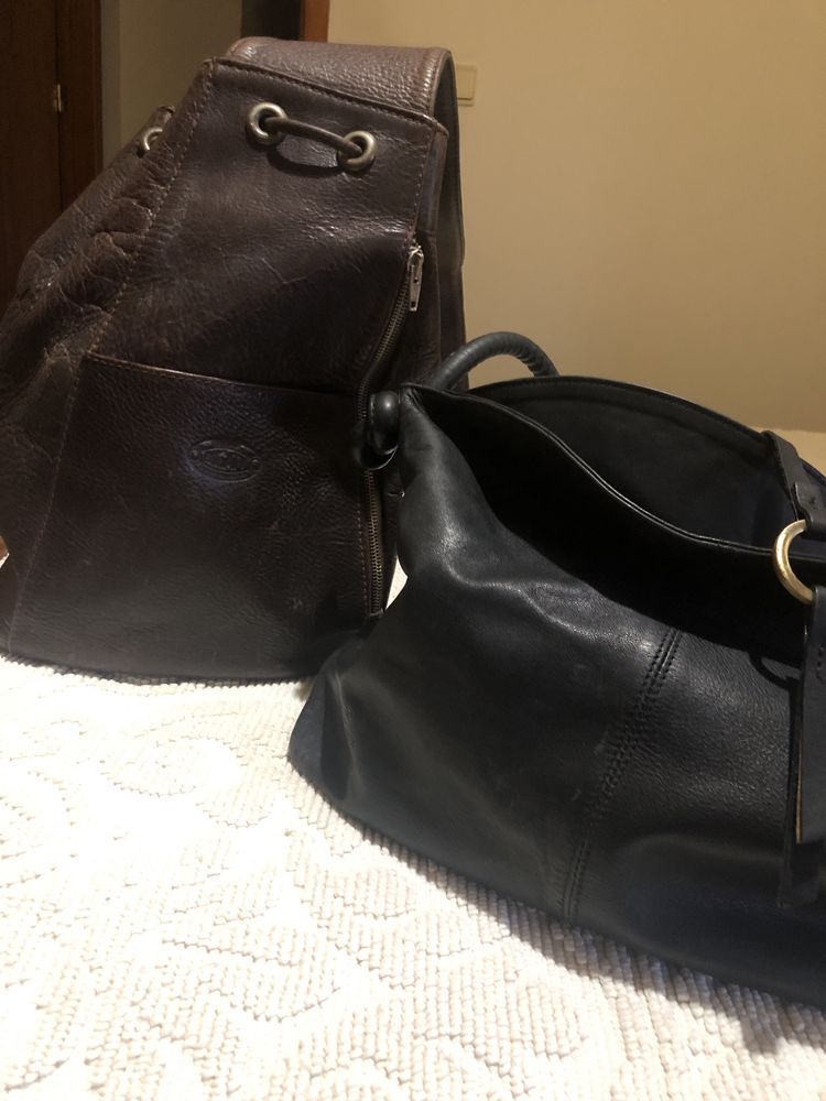 Mochila em pele castanha e bolsa preta . Ambas em pele