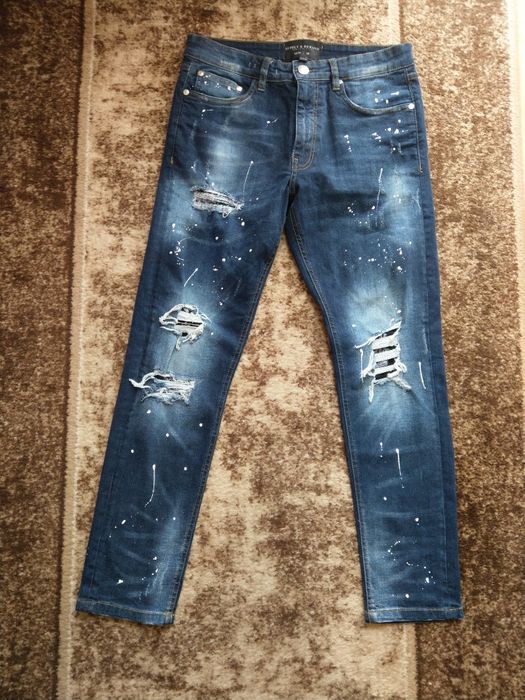 spodnie jeansowe z przetarciami dziurami i kropkami imitujacymi farbe