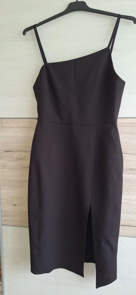 To elegancka czarna sukienka na cienkich ramiączkach, o dopasowanym kr