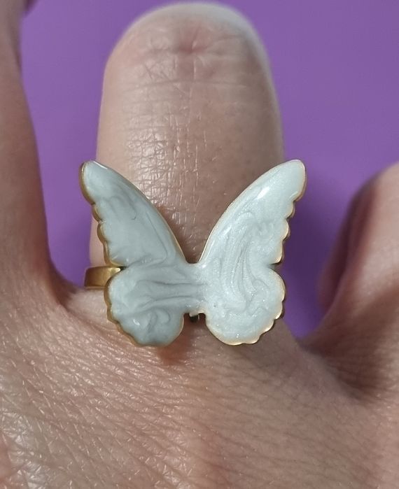 Anel dourado, em açol, com borboleta branca esmaltada. Ajustável