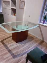 Duży stół ze szklanym blatem na jednej masywnej nodze