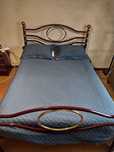 Cama de Casal em ferro com colchão e mesas de cabeceira.