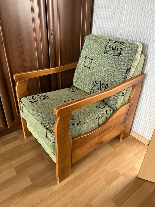 Dwa fotele z zielonego materiału w czarne wzory z drewnianymi bokami