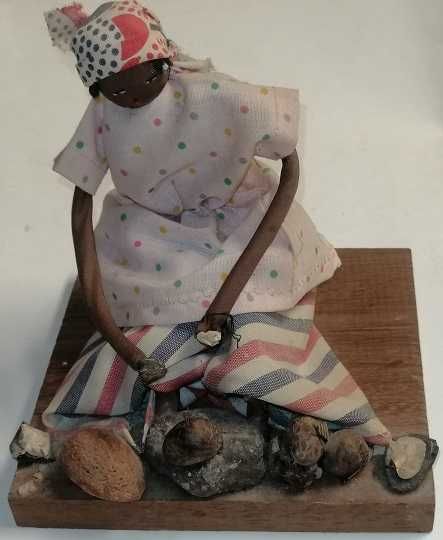 Boneca tradicional africana com trajes do campo num suporte de madeira