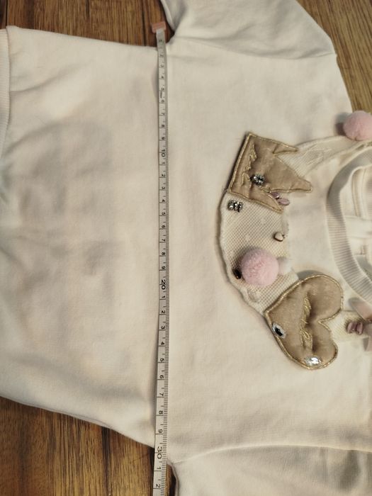 Biała bluza bawełna 80 86 z ozdobną odpinaną dekoracja na dekolcie.