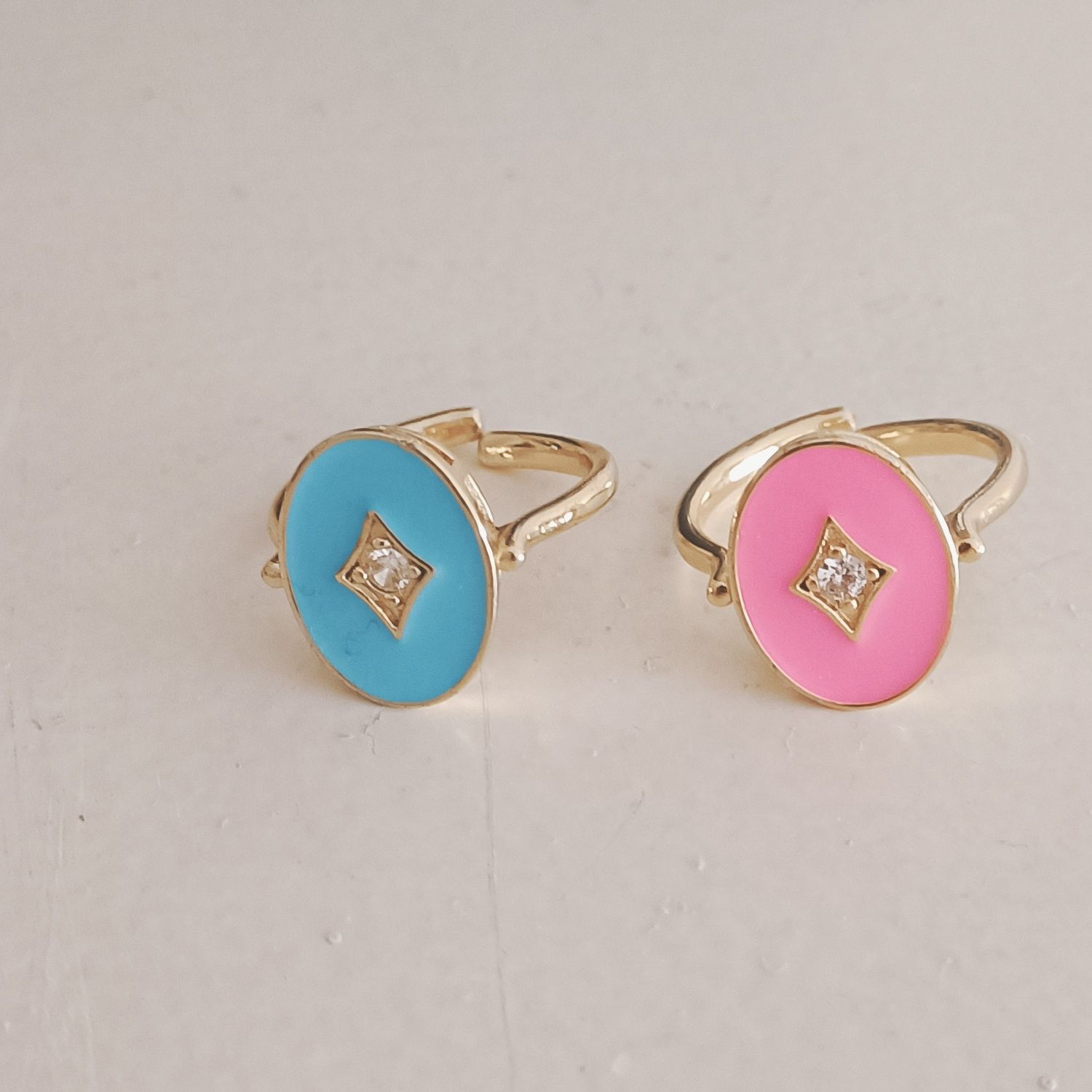 Dois anéis em latão dourado e esmalte rosa e azul.