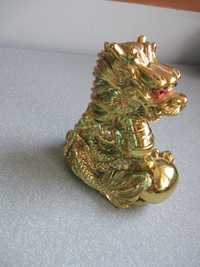 Złota figurka azjatyckiego smoka trzymającego kulę
