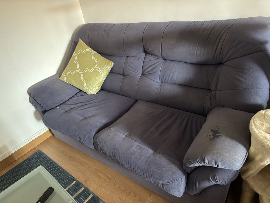 Sofá de sala, azul, com alguns anos e marcas de uso.