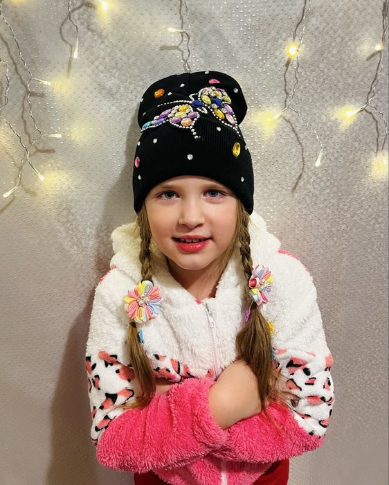 Чорна шапка з яскравим метеликом.