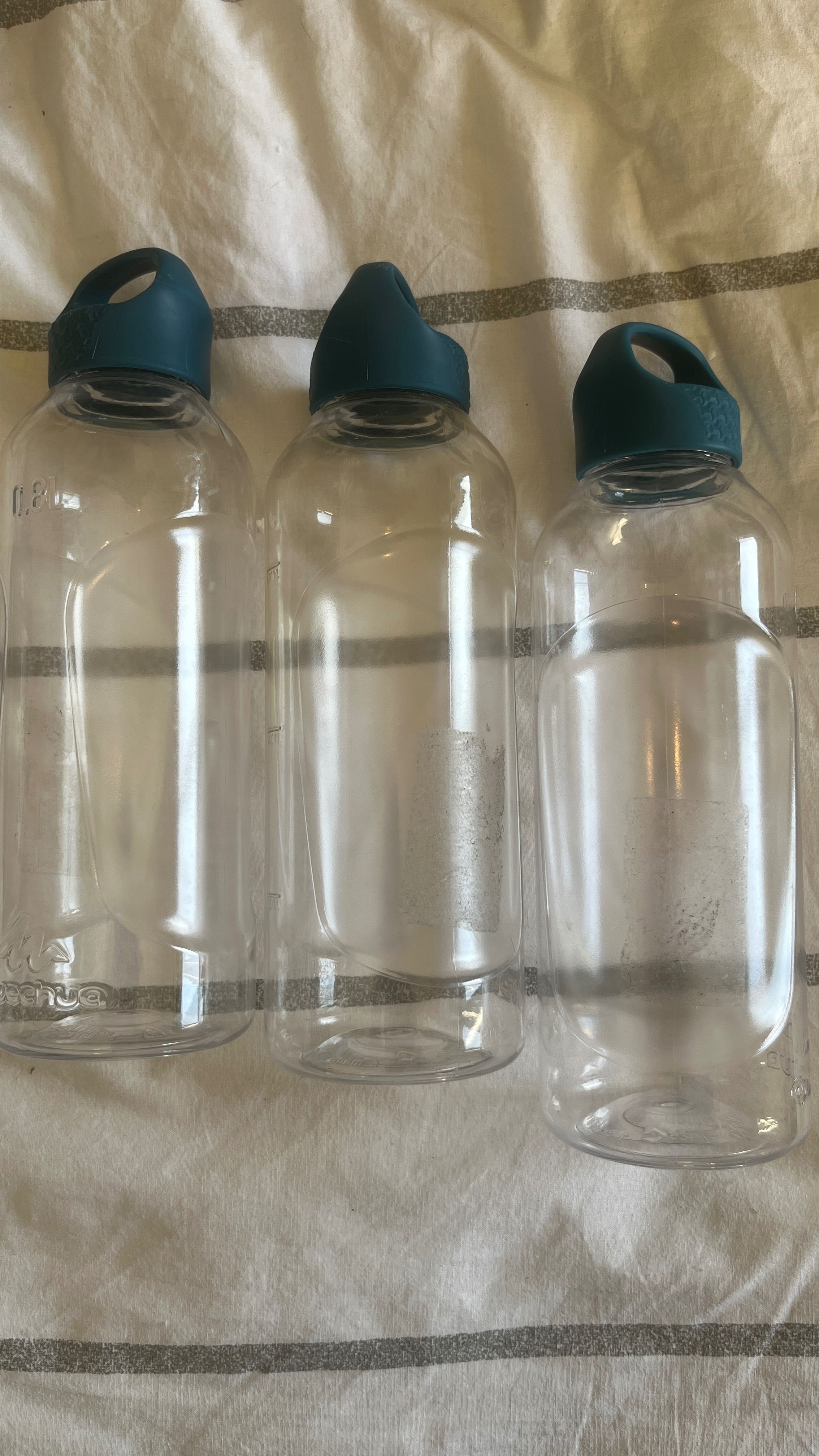 Três garrafas de plástico transparentes, todas com tampa azul.