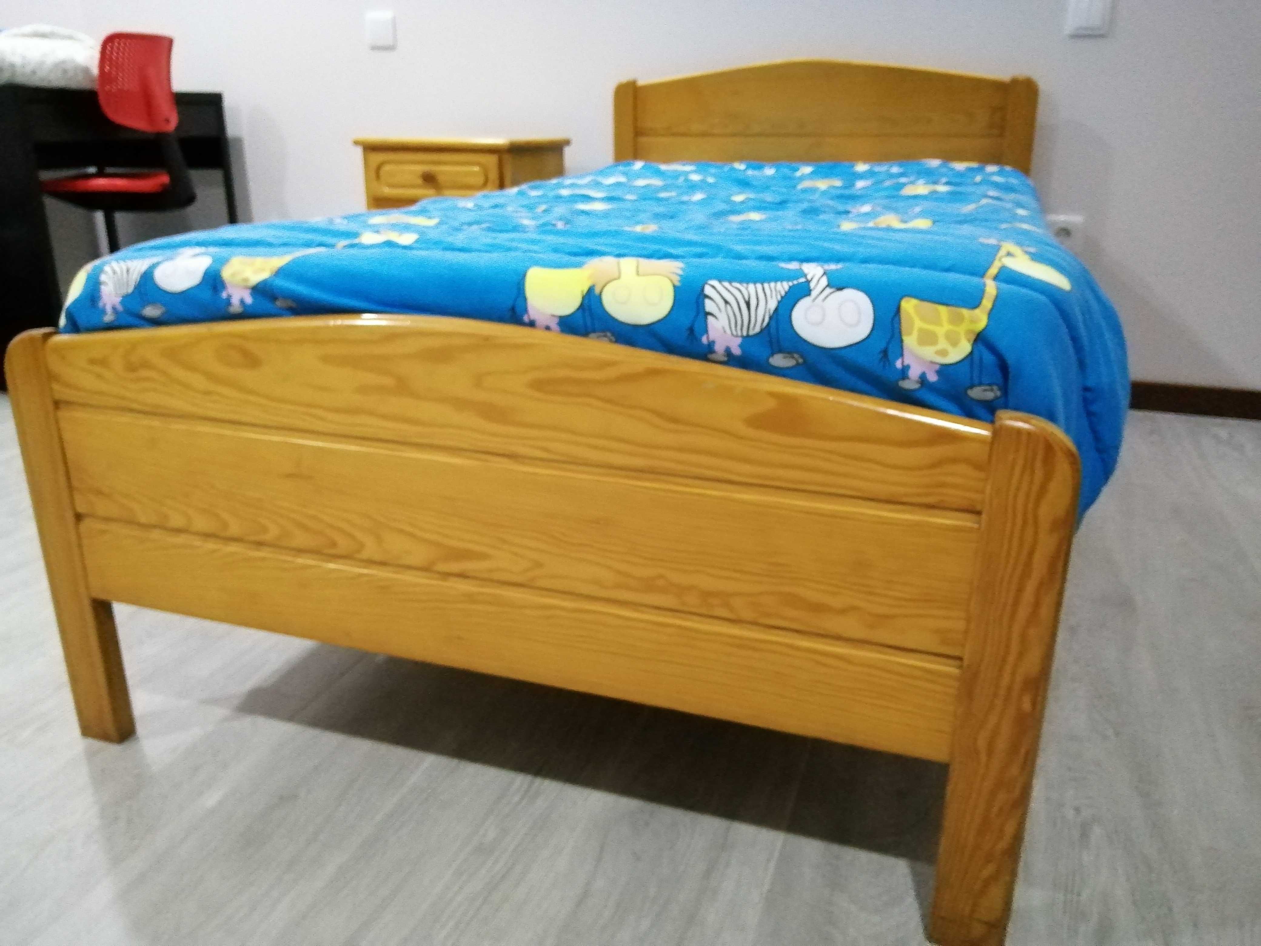 Cama de solteiro com mesinha de cabeceira.