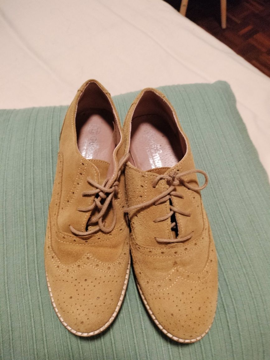Sapatos com biqueira rdonda com atacadores em tecido tipo camurça.