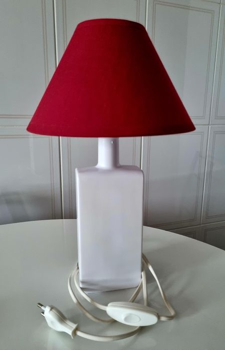 Candeeiro de mesa, feito com uma garrafa branca e abajour vermelho.