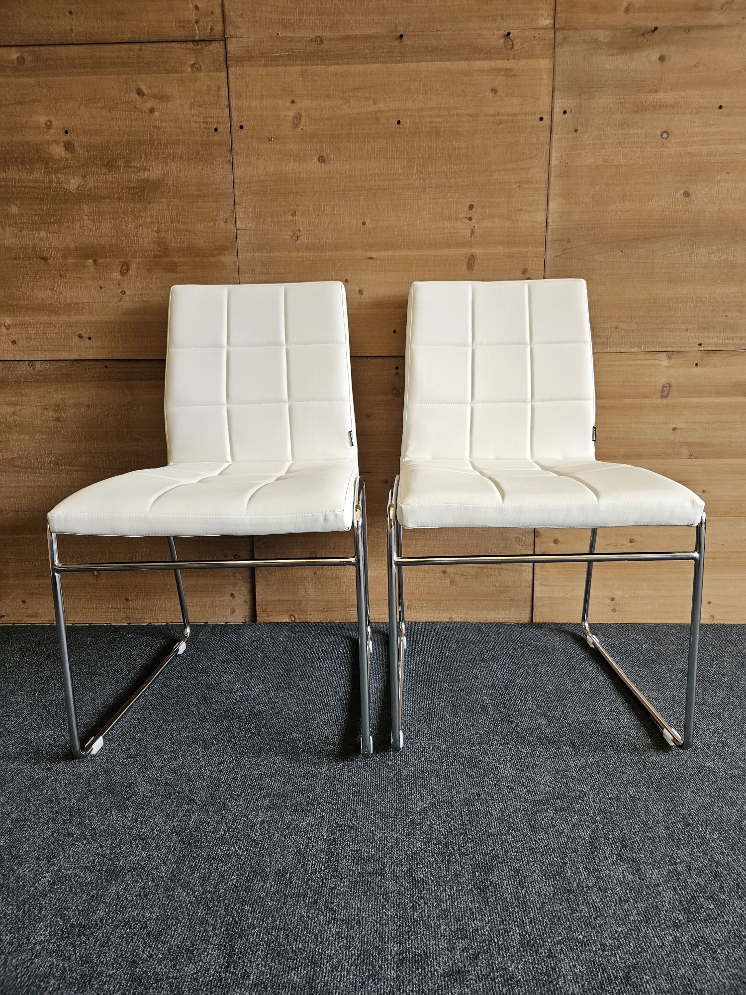 Dwa białe krzesła na chromowanych nogach
