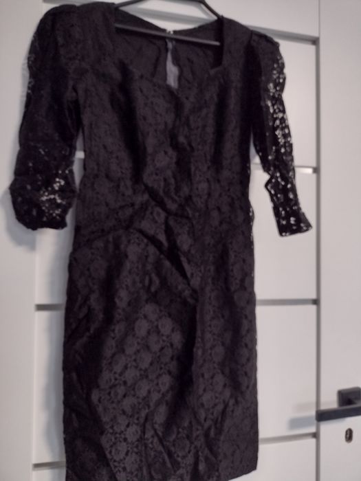 Sukienka szyta z czarnej koronki pienie leży