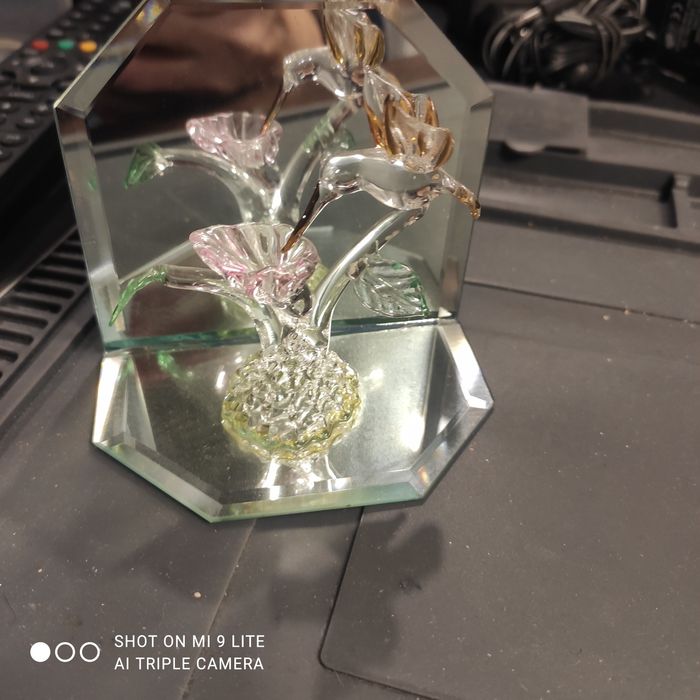 Szklany koliber Swarovski. Statuetka na tle kryształowych luster.