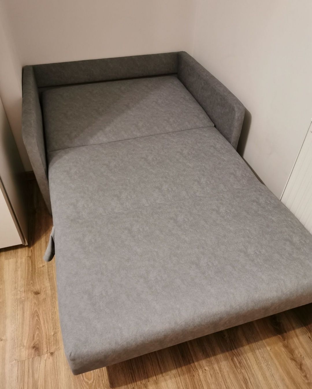 Rozkładana szara sofa z pojemnikiem na pościel