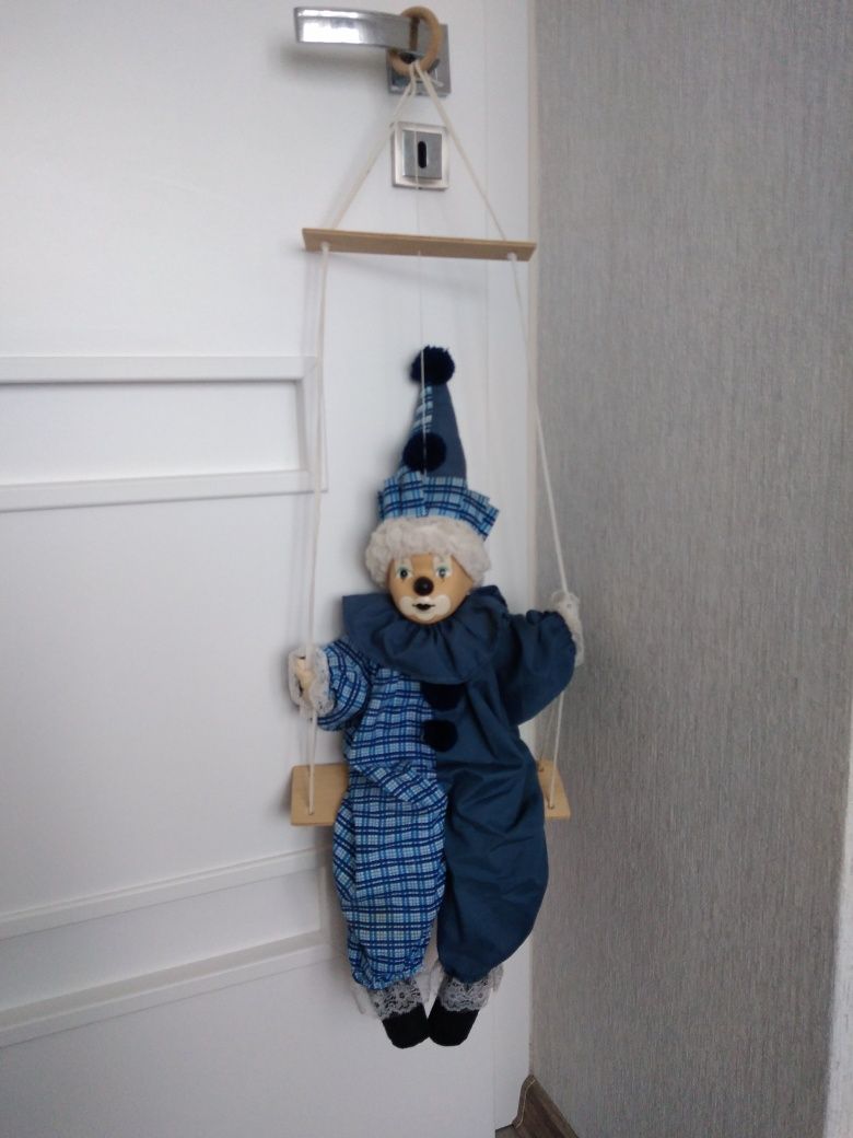 Klaun na huśtawce z porcelanową główką.