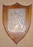 Placa de madeira em formato de escudo com cabeça de cavalo em placa de