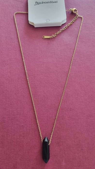 Colar dourado, em aço, com pingente em pedra natural preta lapidada.