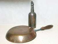 Antiga frigideira e antiga garrafa em cobre