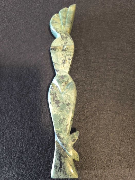 Escultura de mulher em pedra de cor verde.