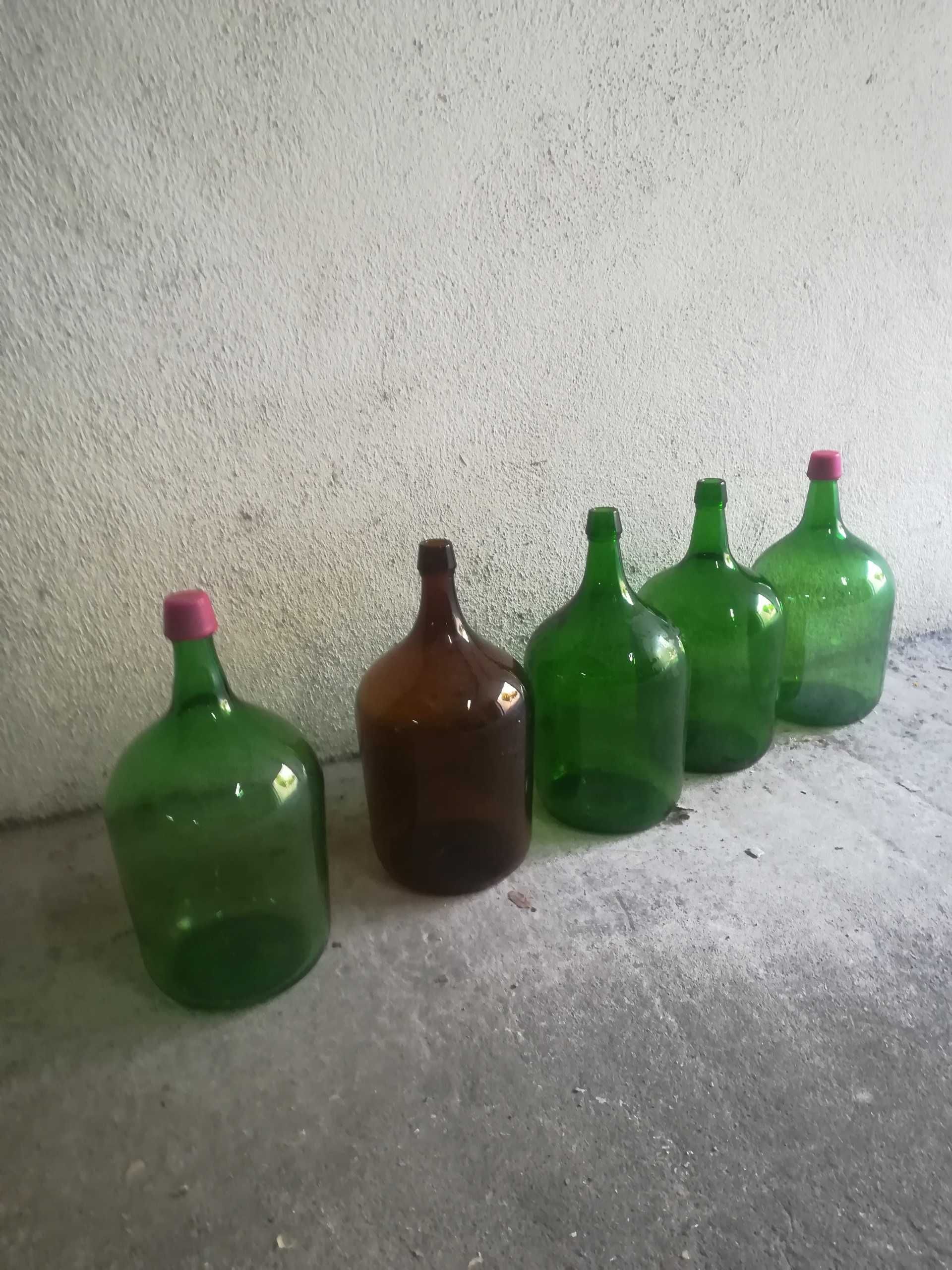 Garrafões de 5 litros em vidro verdes e castanhos.