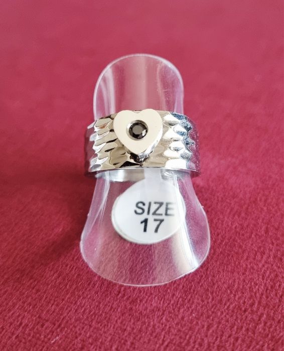 Anel prateado, em aço, com 1 coração com pedrinha preta no centro. T17