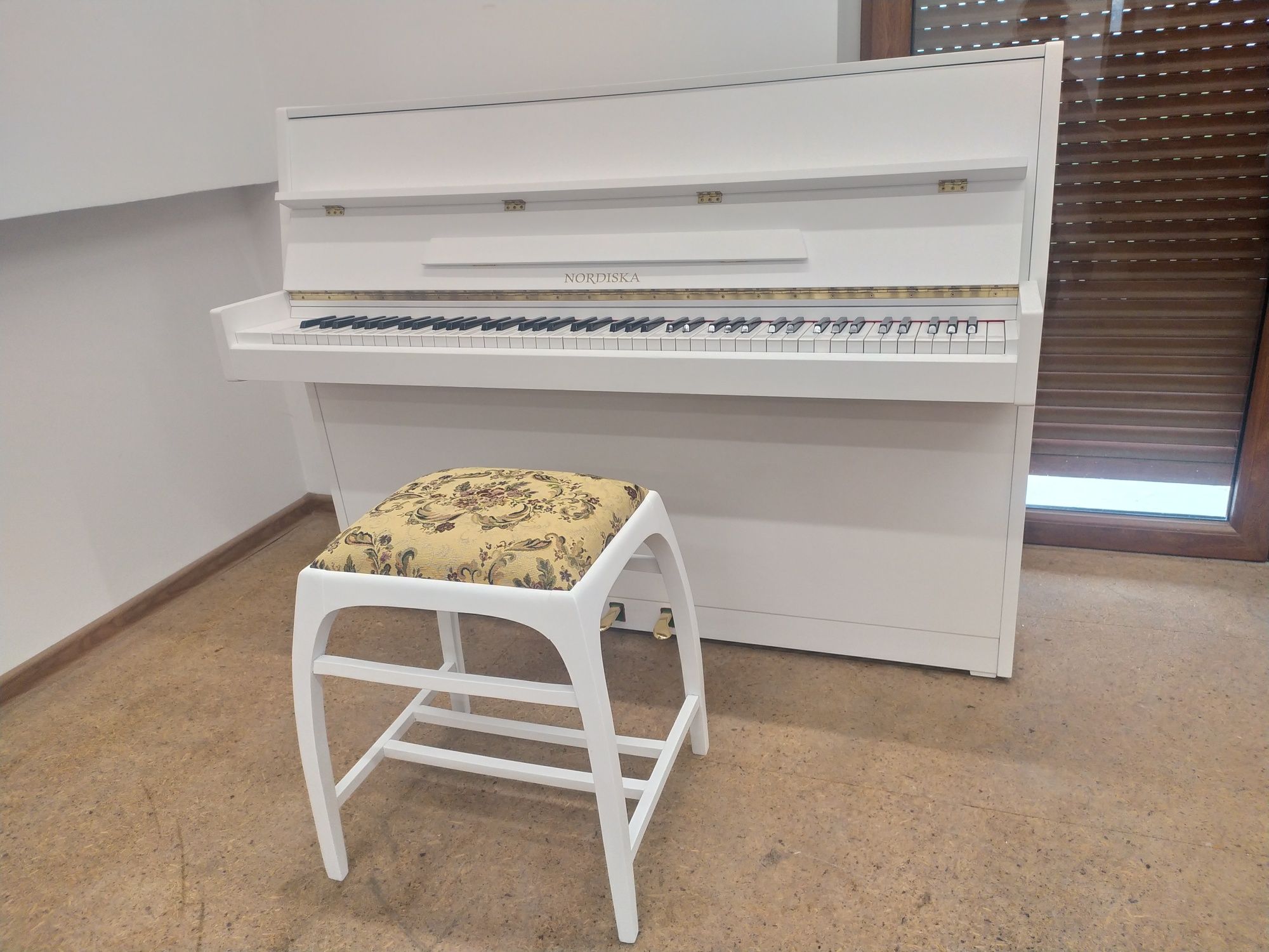Białe pianino Nordiska z mechanizmem Renner
