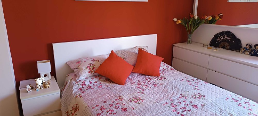 cama de casal com mesa de cabeceira, cômoda e espelho de parede