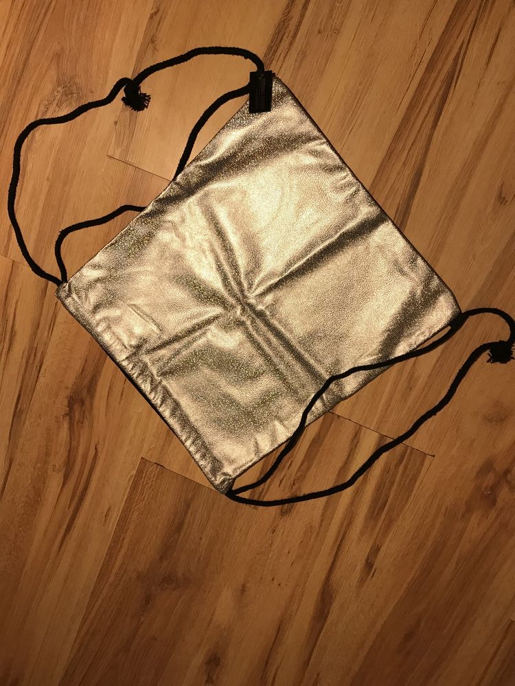 Plecak-worek srebrny błyszczący z płuciennym tyłem.
