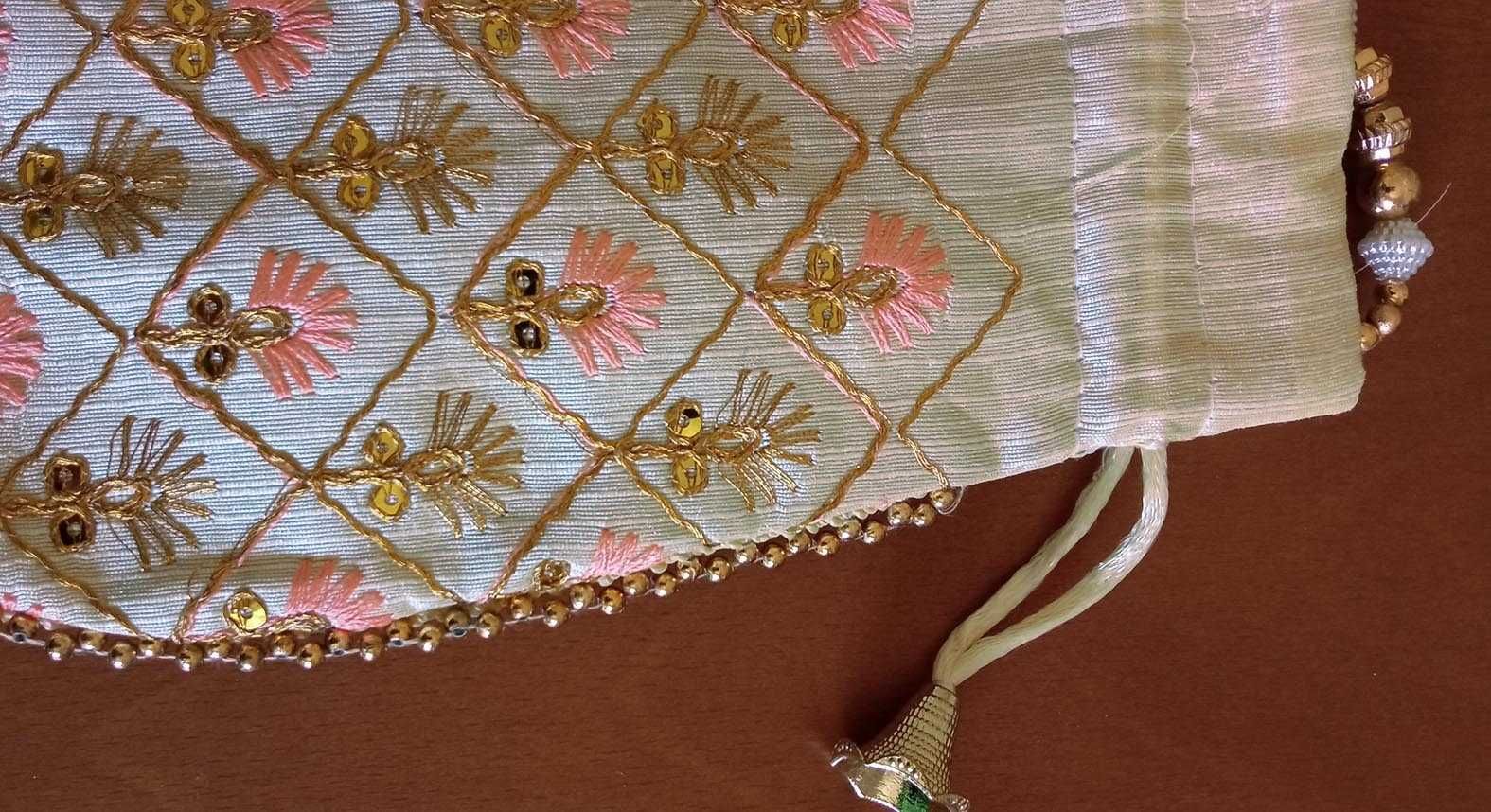 Delicada bolsa de mão branca com bordado floral dourado e coral