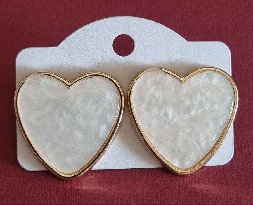 Brincos, de picos, com forma de coração branco delineado a dourado.
