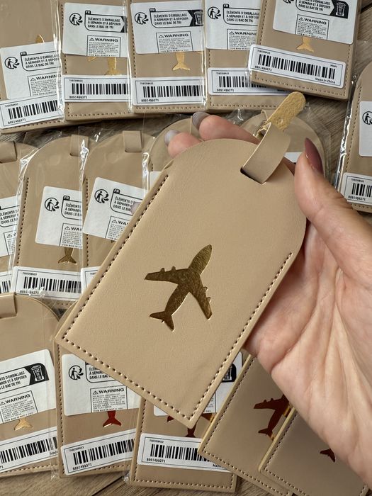 17 Beżowych zawieszek na bagaż ze złotym samolotem - prezent