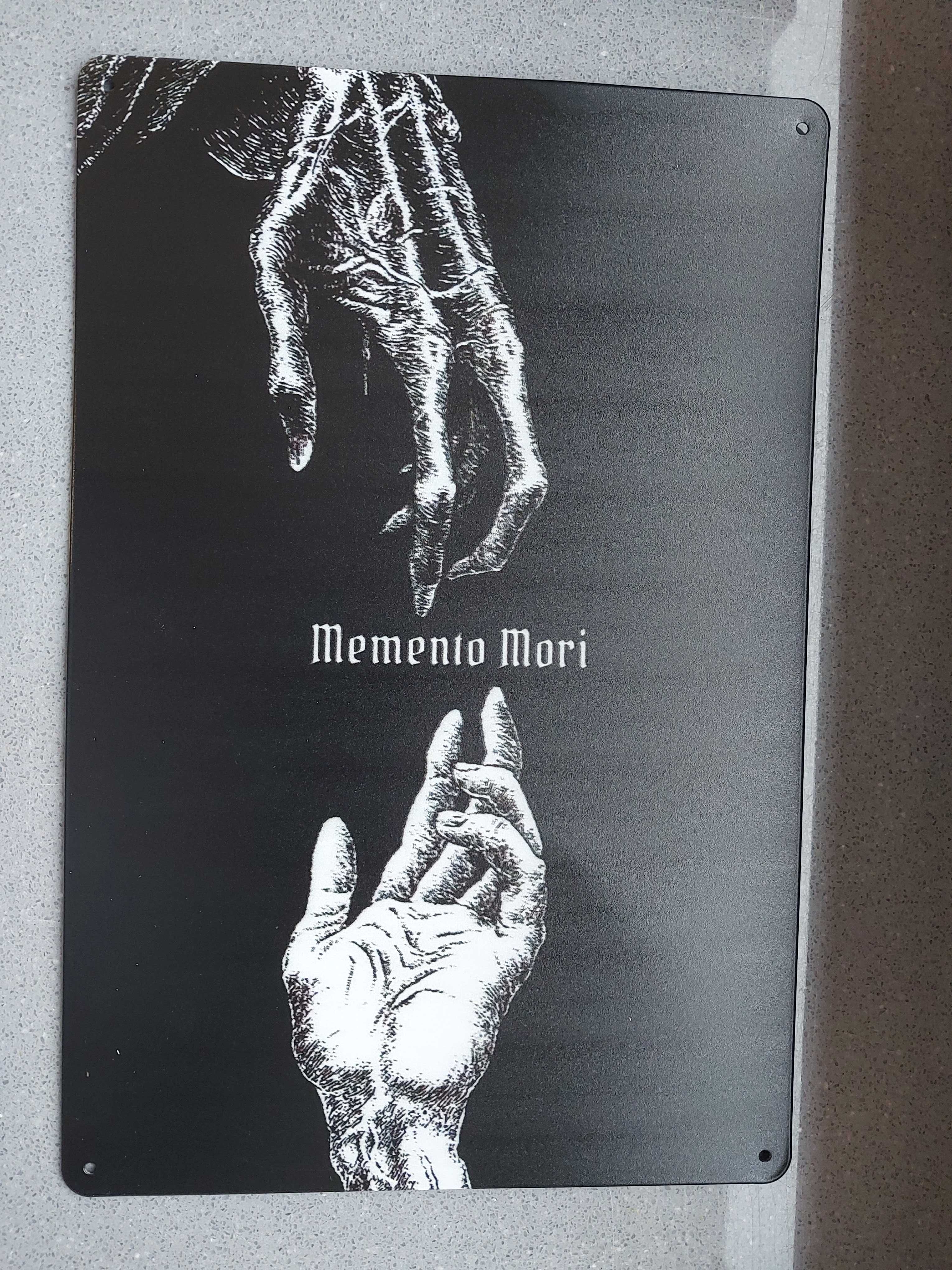 Metalowa tablica z napisem Memento Mori.