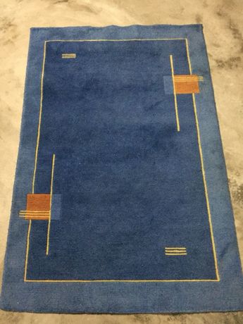 Carpete pelo raso, em azul com apontamentos laranja.