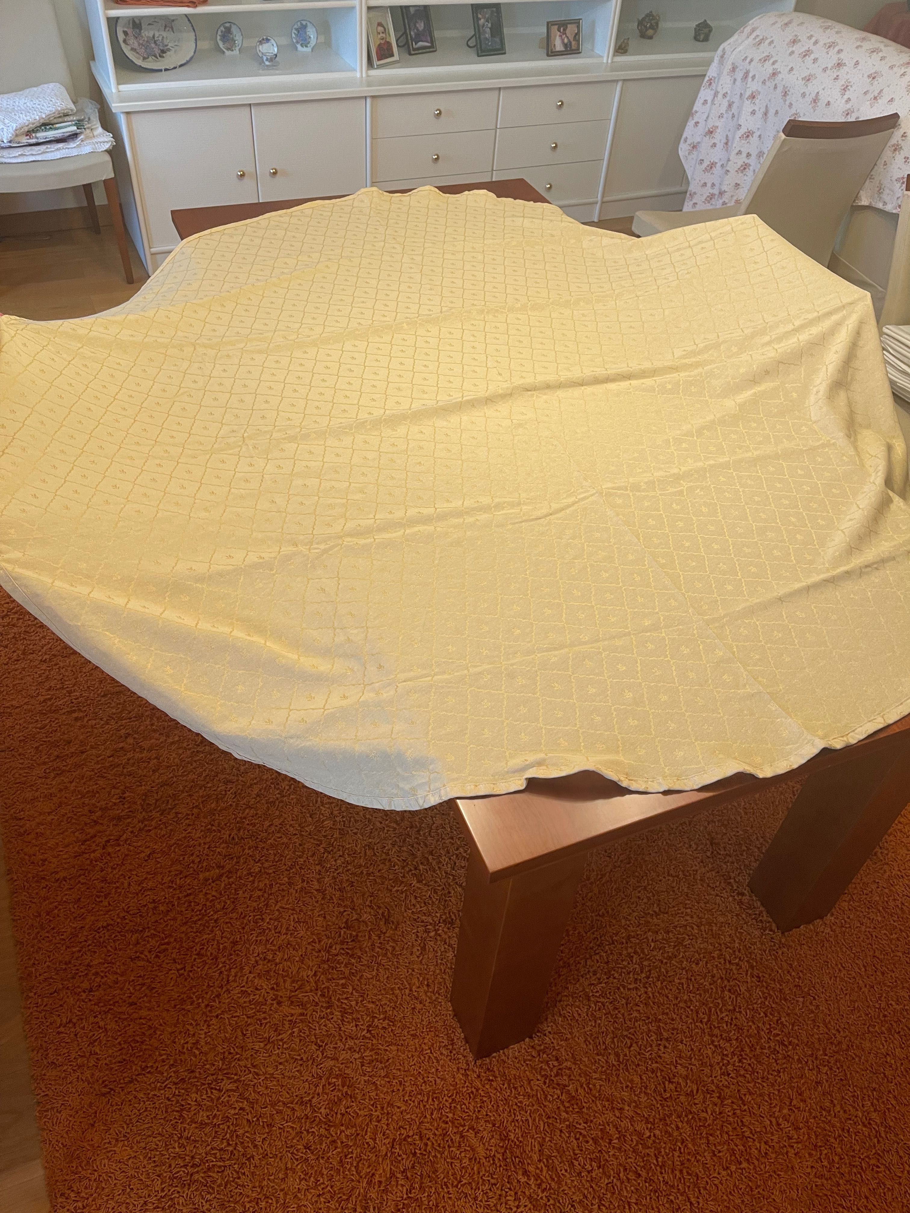 Toalha de mesa redonda em tom creme com detalhes dourados