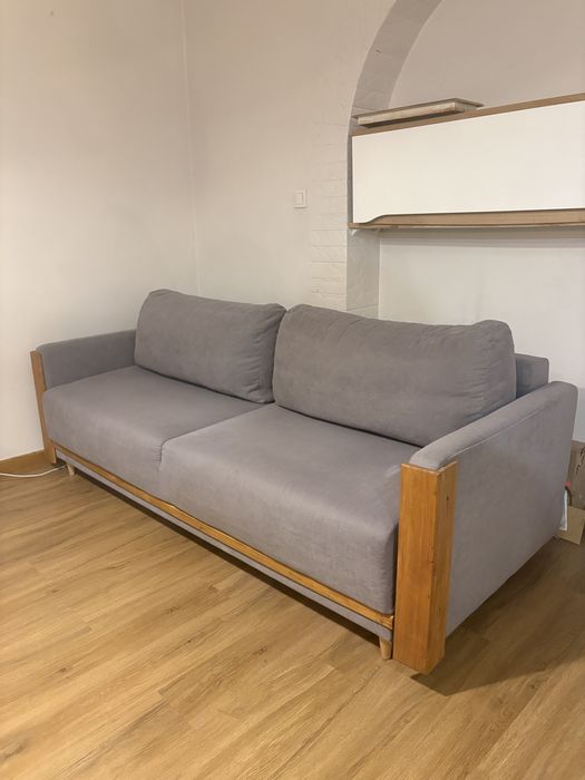 Piękna kanapa rozkładana poduchy łóżko sofa drewniane wstawki szara