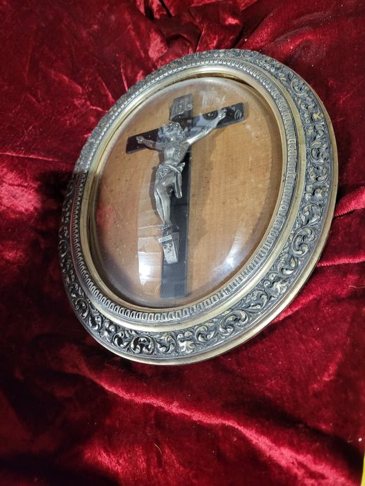 Stary krzyż w owalnej ramie za szkłem