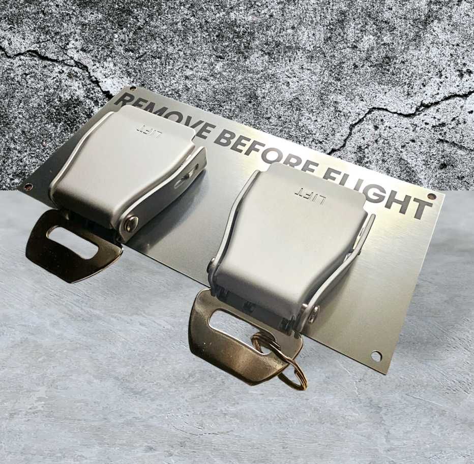 Wieszak na klucze z pasami lotniczymi i napisem REMOVE BEFORE FLIGHT