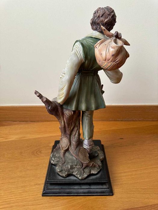 Estatueta de menino com saco ao ombro