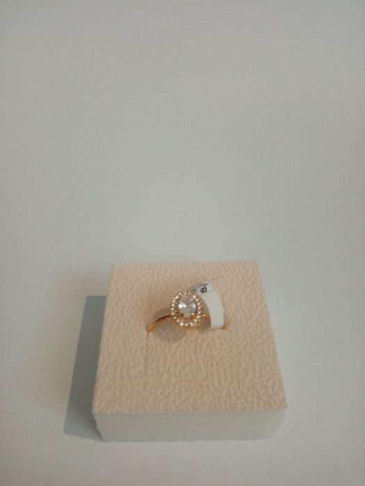 Anel dourado com pequenos cristais a rodear um cristal grande.