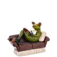 Figurka żaba na kanapie z kawą i książką